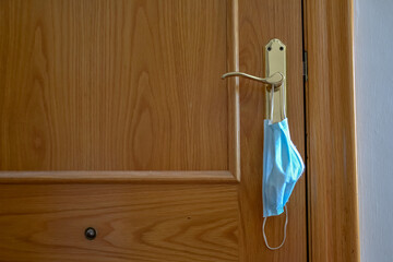 Medical face blue mask hanging on a door knob