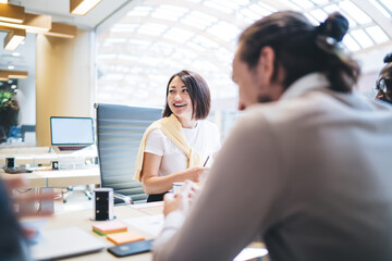 Happy multiracial professionals discussing marketing plan during friendly cooperation at office desktop, successful male and female partners analyzing information enjoying briefing togetherness