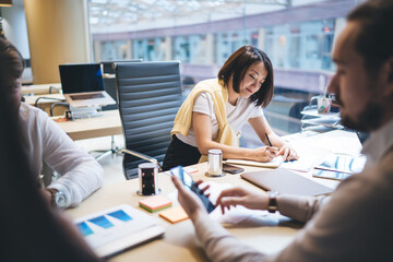 Cheerful woman taking notes during meeting