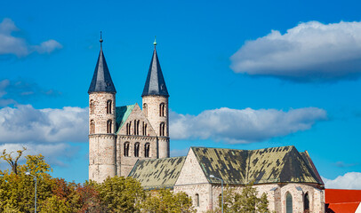 Ancient two towers of Church Monastery of Our Beloved Woman (Kloster Unser Lieben Frauen) in historical downtown of Magdeburg at blue sky with funny clouds in early Autumn, Germany, details.