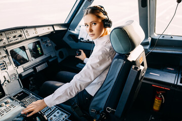 Serious woman pilot flying an airplane, sitting in cockpit.