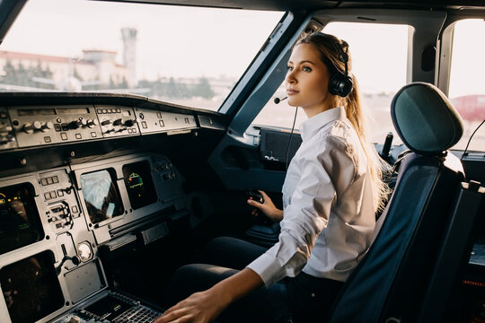 Confident woman pilot flying a commercial aircraft, sitting in cockpit.