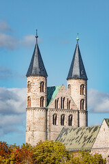 Obraz premium Ancient two towers of Church Monastery of Our Beloved Woman (Kloster Unser Lieben Frauen) in historical downtown of Magdeburg at blue sky with funny clouds in early Autumn, Germany, details.