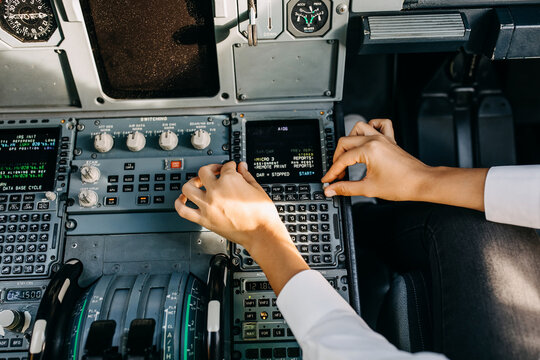 Pilot hands on airplane control board in cockpit.