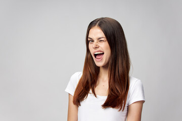 Emotional woman winks she on a light background in a white T-shirt 