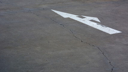 White arrow sign painted on concrete road