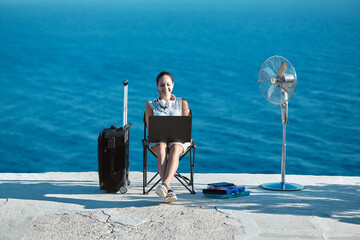 Smiling woman working on laptop on beach. Seascape on background. Life work balance and business...