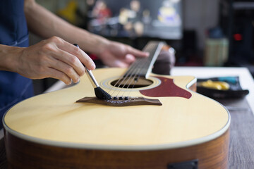 Acoustic guitar care, Craftsman is cleaning the guitar with cleaning brush, Close up.