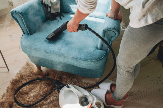 Hand cleaning a armchair with steam cleaner, Home cleaning conce