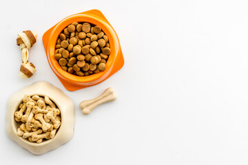 Dry dog food in bowls with bones, top view, copy space