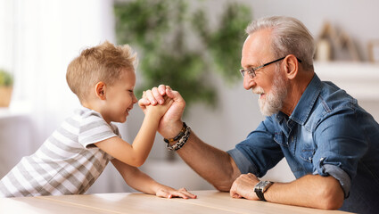 Grandfather arm wrestling with grandson. - obrazy, fototapety, plakaty
