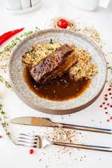 Stewed beef breast with quinoa in a gray marbled ceramic plate. Meat dish in the restaurant. Decor. Top view. Selective focus. Super short focus