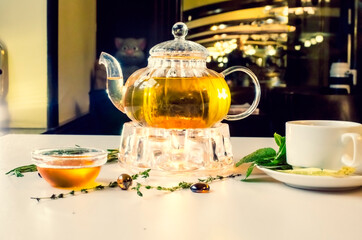 teapot, honey on the table on the background of the cafe. Side view. Kettle warmer. Selective focus. Super short focus