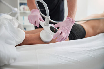 Spa worker pressing an ultrasonic device to patient leg