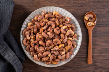 Cashew nuts with peel in a plate on wooden tray and table background, healthy raw food plate.
