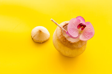 Fresh coconut with straw tropical drink and orchid flower, top view copy space