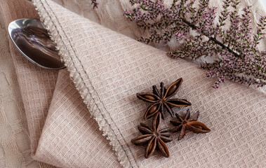  composition of star anise, cane sugar and a flower sprig on a beige napkin