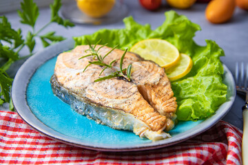 Baked salmon steak with lemon in a plate on the table