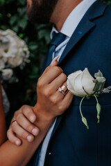 hand in hand with a wedding ring on the background of a jacket with a boutonniere, wedding theme