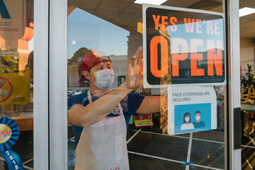 LOS ANGELES, UNITED STATES - Aug 02, 2020: Store employee posting an OPEN sign during covid-19 pandemic at S&S Donut, Los Angeles