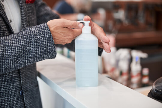 Responsible senior citizen sanitizing his hands at the counter