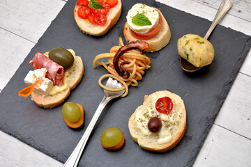 varietà di tapas con ingredienti italiani mozzarella gorgonzola pomodori olive polpo spaghetti salame frittelle di alghe di mare cibo mediterraneo