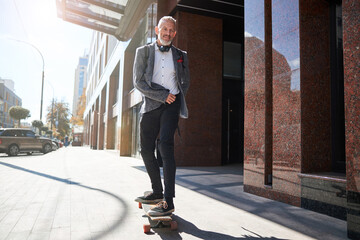 Joyous senior citizen being happy on his longboard