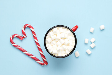 Hot drink with marshmallows  in red cup on pastel blue background. Holiday festive celebration greeting card with copy space
