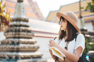 Young adult traveller asian woman writing memo journal list.