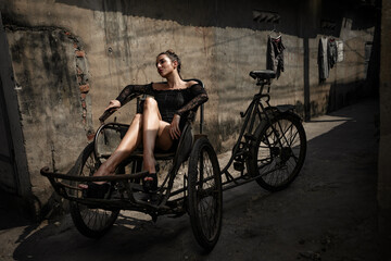 Fototapeta na wymiar Urban portrait of gorgeous Young woman on vietnamese tricycle on the slum