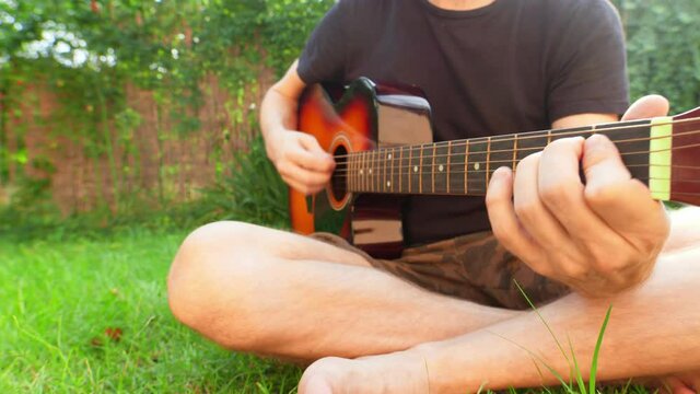 Man sitting in the grass playing guitar