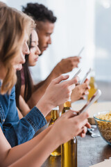 selective focus of multiethnic friends chatting on mobile phones during party