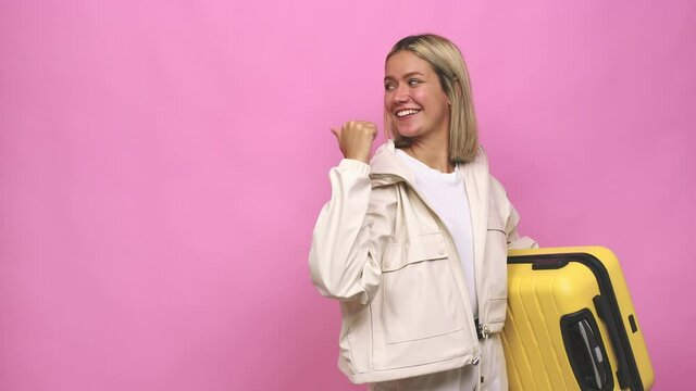 Young blonde woman ready for a travel points with thumb finger away, laughing and carefree