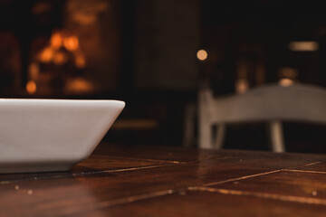 Un cuenco blanco sobre una mesa de madera vacía en un restaurante