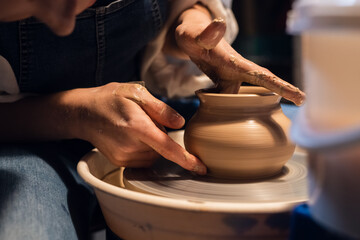a master in a pottery workshop shows the technique of modeling a pot on a potter's wheel