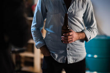 friends guys gathered at a bachelor party in the garage, drinking beer from dark bottles at a party
