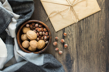 Nuts hazelnuts and walnuts in a cup, letter, plaid. Wooden background. Autumn composition.