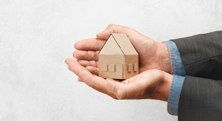 Hand holds house. Buying or selling home, real estate insurance. Protection and safety life.