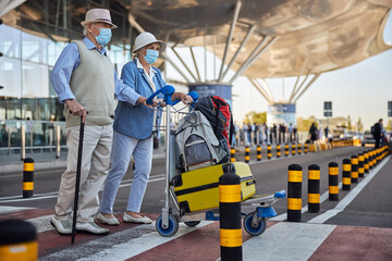Fototapeta na wymiar Aged tourists wheeling a trolley with their luggage