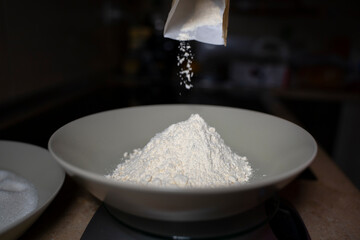Pouring flour into a deep plate. Low light.