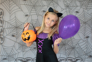 funny little girl in witch costume for Halloween on spiderweb background