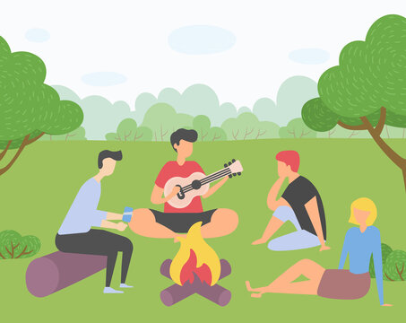 Young company of friends on picnic outside the city. Campfire gatherings, singing songs on the guitar, shoot on smartphone. Trip out of town or city park. Rest and vacation. Harvest festival in Europe