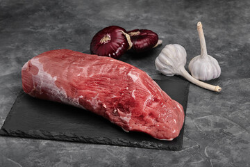 Fresh tenderloin with rosemary, raw meat, top view, on a stone background.