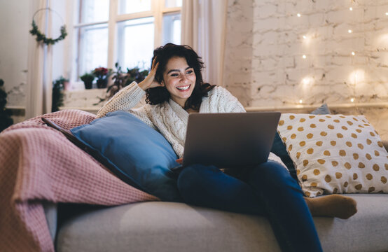 Happy woman using laptop on cozy sofa