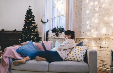 Young woman resting near Christmas tree at home