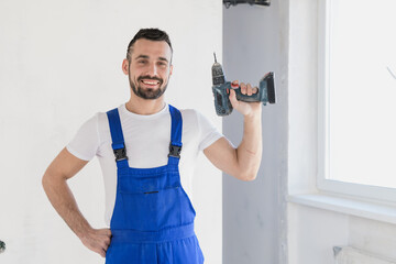 A male worker holds a drill in his hand and looks at the camera