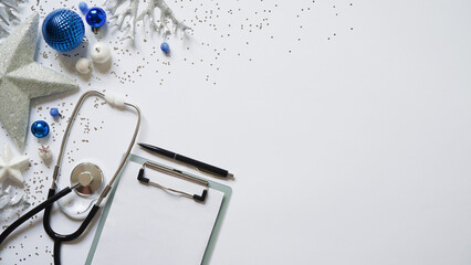 Christmas medical banner christmas decor white stars,blue balls, snowflakes, stethoscope and tablet on white background top view. Copyspace. Medicine new year flatly. Doctor writes down the text
