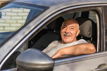 Senior man driving a car, looking at the camera. driving concept. 