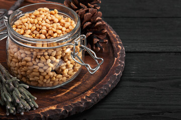 Pine nuts in a glass dish on a dark background with nuts scattered around