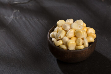 Zea mays - Wooden bowl with fresh corn kernels.